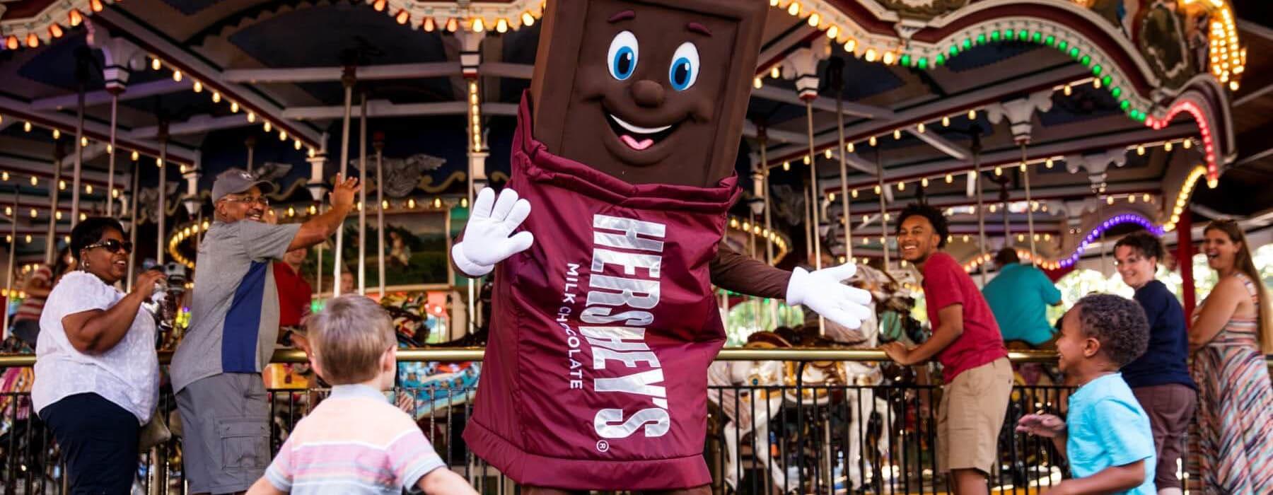 Children running to Hershey's character in front of the Carrousel at Hersheypark