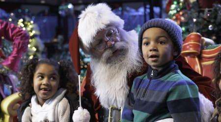 Two little kids sitting with Santa